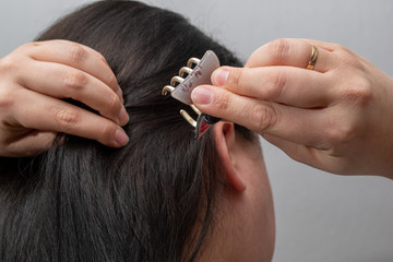 Frau klemmt haarklammer ins lange schwarze haar