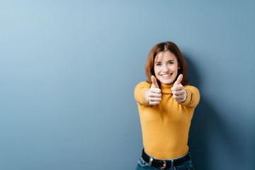 Elated young woman giving a double thumbs up