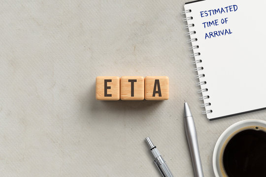 cubes with acronym ETA and notepad with explanation ESTIMATED TIME OF ARRIVAL on paper background