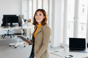 Smiling young woman with tablet pc in office