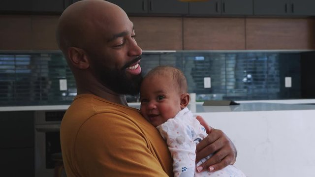 Smiling African American Father Cuddling And Playing With Baby Daughter Indoors At Home