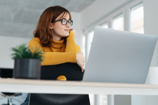 Low Angle Portrait Of Dreamy Young Woman In Office