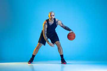 Young basketball player of team wearing sportwear training, practicing in action, motion isolated...