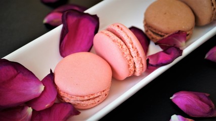 multicolored french macarons with rose petals on a white dish