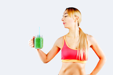 Sport blond girl in tracksuit for sport exercises with glass of green smoothie