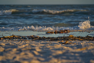 Gischt und schäumende Wellen am einsamen Naturstrand während des Sonnenuntergangs