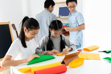 Young diversity Asian students enjoy activity in classroom. Boys, girls learning together by use colorful paper. Integrated school educate children in an environment where self-esteem and independence