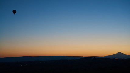 Silhouette of a flying hot air balloon in the clear sky at sunrise in Cappadocia, Central Anatolia, Turkey.