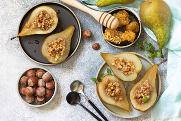 Healthy diet dessert. Baked pears with hazelnuts, honey and granola on a slate, stone or concrete background. Top view flat lay background.
