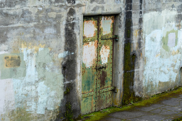 Fototapeta na wymiar Landscape of old metal door in a grey concrete wall