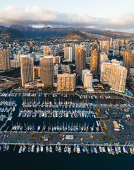 Honolulu city and marina at sunset. Hawaii O'ahu marina, boats floating infront of the city with mountains behind.  Travel and Tourism