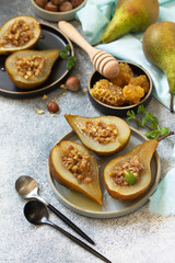 Healthy diet dessert. Baked pears with hazelnuts, honey and granola on a slate, stone or concrete background.
