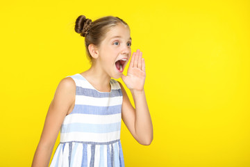Young beautiful girl screaming on yellow background