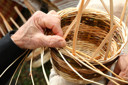 senior craftsman while creating a wicker basket