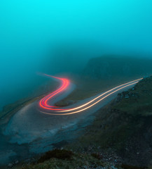 Car Lights in the mist travelling round hairpin bend in the mountains.  Cool colors and warm lights