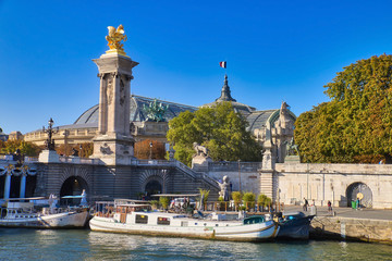 Fototapeta na wymiar Pleasure boats docked on the Seine river next to the Alexander III Bridge, one of the most beautiful bridges that cross the Seine river, in Paris, France.