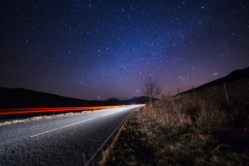 Car lights beneath the starry sky. Speed, calm peaceful travel