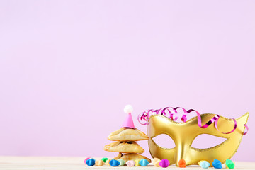 Purim holiday composition. Cookies with party supplies on pink background