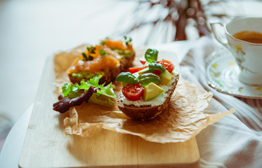 Wholegrain toast with avocado, tomato and salmon on wooden cutting board