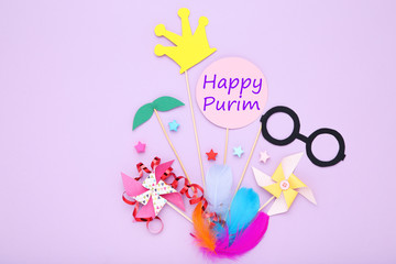 Purim holiday composition. Party supplies with text Happy Purim on purple background