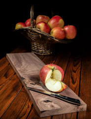Cut apple  in front of basket of apples on black background