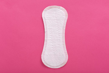 Horizontal indoor picture of clean unused unpacked sanitary pad, ready to be used, being disposable, located in middle of photo, feminine hygiene during menstruation concept. Flat lay. Top view.