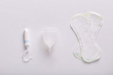 Picture of various kinds of products for menstruation. Hygiene pads, white menstrual cup and tampon lying on white surface. Alternative ways for critical days. Women and their problems concept.