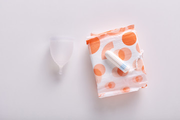 Horizontal flat lay of different types of feminine hygiene products for menstruation. Menstrual cup, packed sanitary pad and tampon laying on it, being isolated over white background. Periods concept. © sementsova321