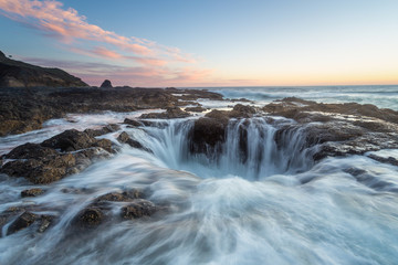 Thor's well Oregon Coast, waves crashing over rocks and into blowhole during a beautiful sunset