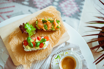 Wholegrain toast with avocado, tomato and salmon on wooden cutting board