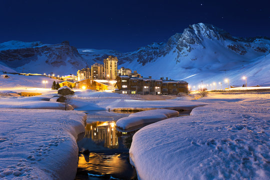 Ski resort at night. French Ski resort Tignes, beneath towering mountains, night time Blue Hour.  Skiing Snowboarding