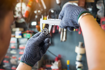 Mechanic man using a Vernier caliper to measure Bearings at motorcycle shop , selective focus