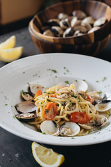 Pasta with clams on white plate on black background. Mediterranean delicacy food. Flat lay. Top view
