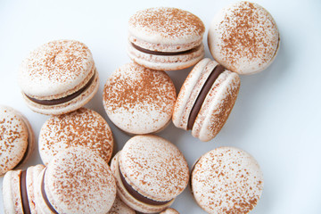 French dessert macaron powered with cocoa powder and filled with dark chocolate ganache. On a white background. Top view.