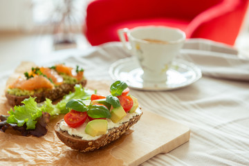 Fototapeta na wymiar Wholegrain toast with avocado, tomato and salmon on wooden cutting board