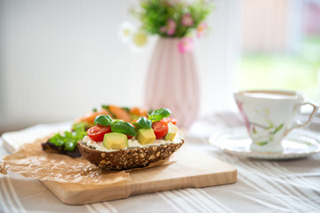 Wholegrain toast with avocado, tomato and salmon on wooden cutting board
