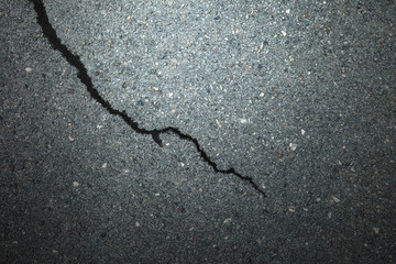 Image of a large black crack on a flat rocky background. Cracked wall surface.