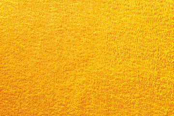 Texture of yellow natural cotton beach towel. Fluffy soft and delicate terry cloth sand background, textured fabric closeup macro.