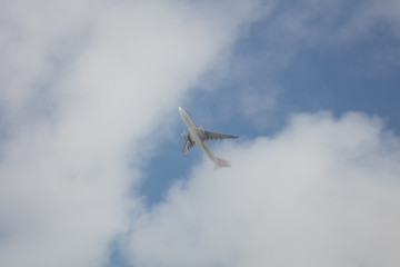 Passagierflugzeug im Steigflug hinter leichten Wolken
