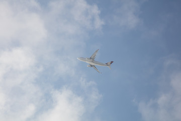 Passagierflugzeug im Steigflug hinter leichten Wolken