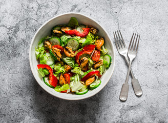 Salad with fresh vegetables and canned mussels on a gray background, top view. Delicious healthy...