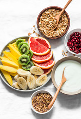 Breakfast set table - fresh tropical fruits, greek yogurt, granola on a light background, top view. Delicious healthy diet food concept. Flat lay