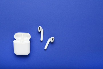 White wireless earphones on blue background