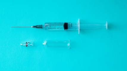 A syringe filled with medicine with an opened ampoule on a blue background. Healthcare and medicine concept. Intramuscular injection. Vaccine in an ampoule.