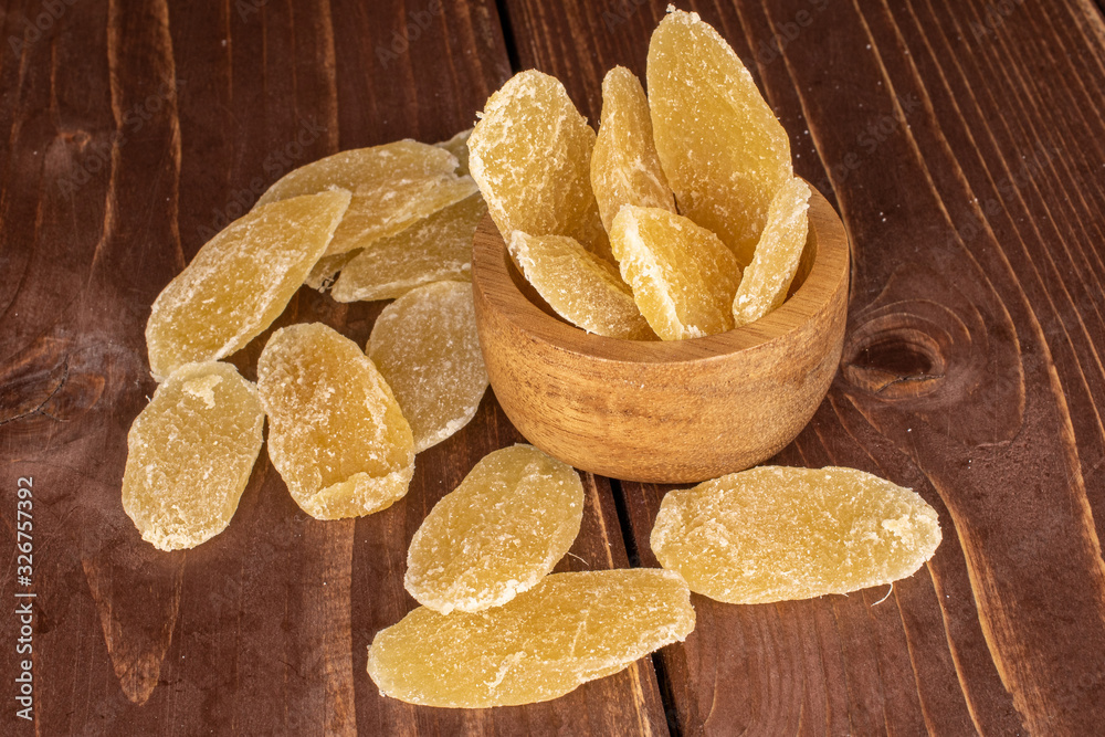 Wall mural Lot of slices of dried yellow pineapple in bamboo bowl on brown wood