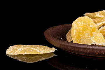 Lot of slices of dried yellow pineapple with brown ceramic coaster isolated on black glass