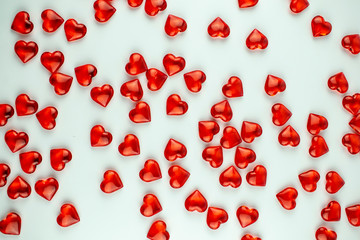 A scattering of scarlet crystal hearts on a white background.