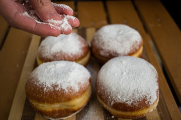 Woman hand sprinkle donuts with powdered white sugar