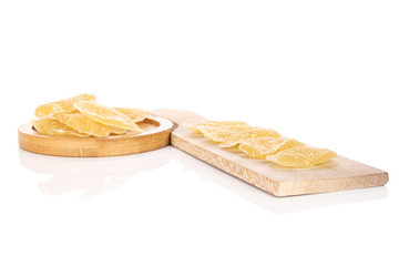 Lot of slices of dried yellow pineapple on wooden cutting board with brown ceramic coaster isolated on white background