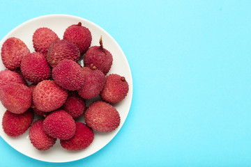 Tasty lychee in plate on blue background